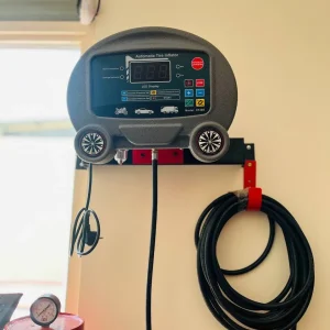 An automatic tire inflator mounted on a wall. The device features a digital LED display and several buttons for controlling tire inflation. It includes icons representing different types of vehicles, such as motorcycles, cars, and trucks. The model number "CT469" is visible on the device. Below the inflator, a coiled black hose with a pressure gauge is attached to a red cylinder. The buttons are labeled with functions such as "Increase Pressure," "Decrease Pressure," "Transform Pressure Unit," "Start," and "Stop."