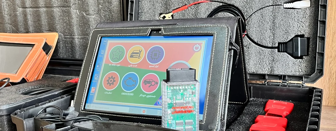 The image shows an open black plastic case with red latches containing various electronic diagnostic tools and cables. The case is divided into compartments with foam padding to securely hold the items. Inside the case, there are several cables with different connectors, including red and black clips, and a tablet-like device with a colorful interface displaying icons for different functions. The tablet is connected to a circuit board with a green PCB and various electronic components. The case also contains additional red connectors and a black zippered pouch. The setup appears to be a diagnostic tool kit, likely used for automotive or electronic diagnostics, making it relevant for technicians or engineers who need to troubleshoot and repair electronic systems