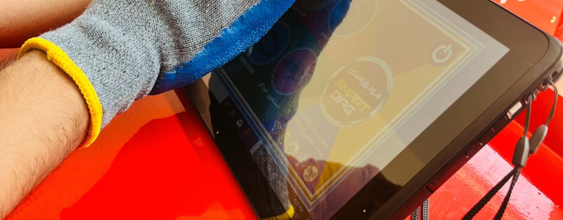 "A person wearing a blue and gray glove cleans a tablet screen with a cloth. The tablet rests on a red surface. In the background, there is a machine labeled 'Rebuilder Charging Machine' with the model number 'C-730.' Two chairs are also visible. The image includes Persian text that translates to 'Golden tips for maintaining diagnostics.
