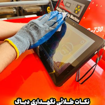 "A person wearing a blue and gray glove cleans a tablet screen with a cloth. The tablet rests on a red surface. In the background, there is a machine labeled 'Rebuilder Charging Machine' with the model number 'C-730.' Two chairs are also visible. The image includes Persian text that translates to 'Golden tips for maintaining diagnostics.